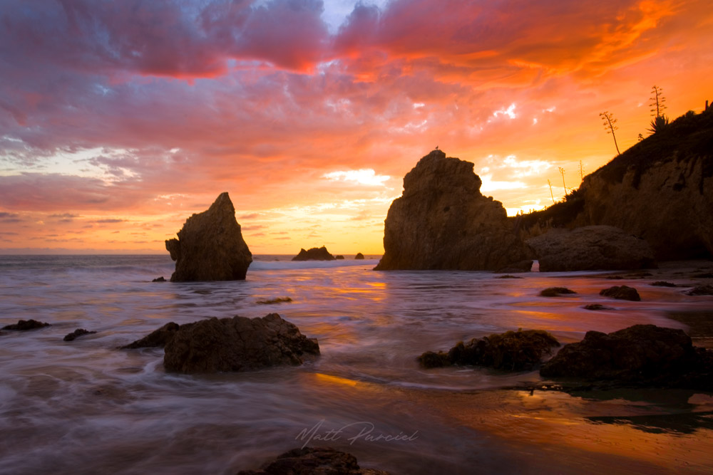 El Matador Beach sunset in Malibu with fiery sky over dramatic sea stacks and rock formations