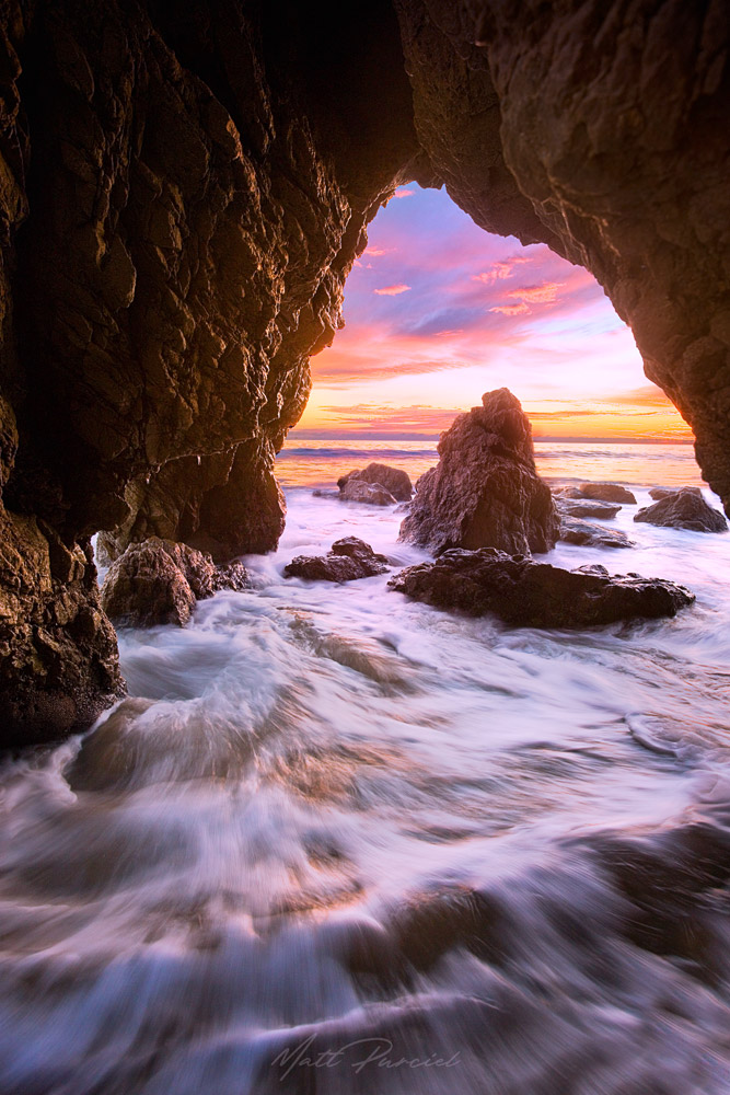 El Matador Sea Cave in Malibu framed by crashing waves and golden light at low tide