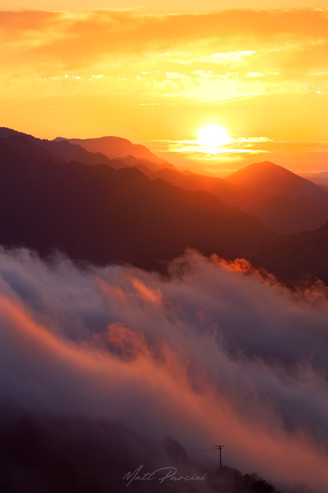 Santa Monica Mountains sunset with layers of fog illuminated by golden light over the Malibu coast